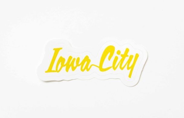 A product photo of the script Iowa City word mark logo with yellow text, printed by Sticker Giant is seen photographed for Shop Think Iowa City, Tuesday, Sept. 24, 2024, in Coralville, Iowa. MANDATORY CREDIT: Joseph Cress/Think Iowa City